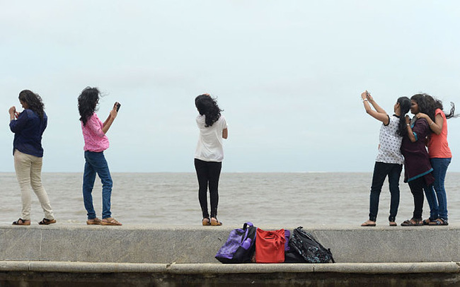 Khách du lịch chụp ảnh trên bãi biển ở thành phố Mumbai. (Ảnh: AFP) 