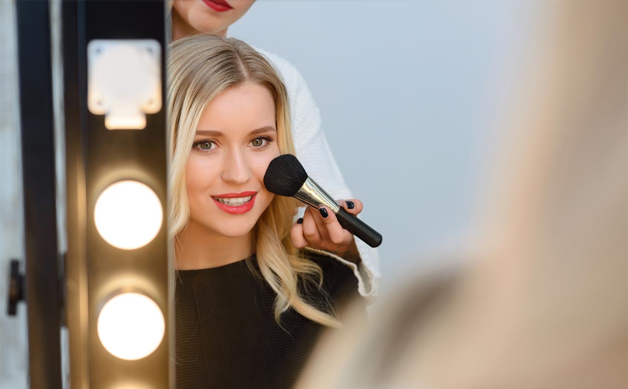 lady-applying-makeup-in-lighted-mirror